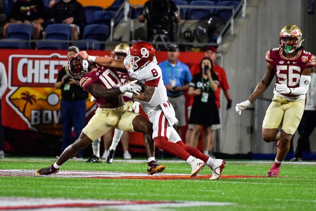 Oklahoma Sooners quarterback and former UCF Knight Dillon Gabriel (#8) shoves FSU defensive back Jammie Robinson (#10)'s by the facemask as he runs the ball during the 2022 Cheez-It Bowl at Camping World Stadium Thursday, December 29, 2022. Photo: Harry Castiblanco/Florida National News.